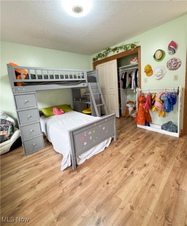 bedroom featuring a closet, a textured ceiling, and wood finished floors