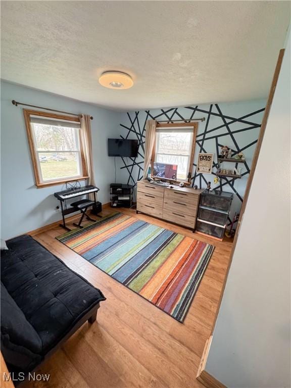 bedroom with baseboards, multiple windows, a textured ceiling, and wood finished floors