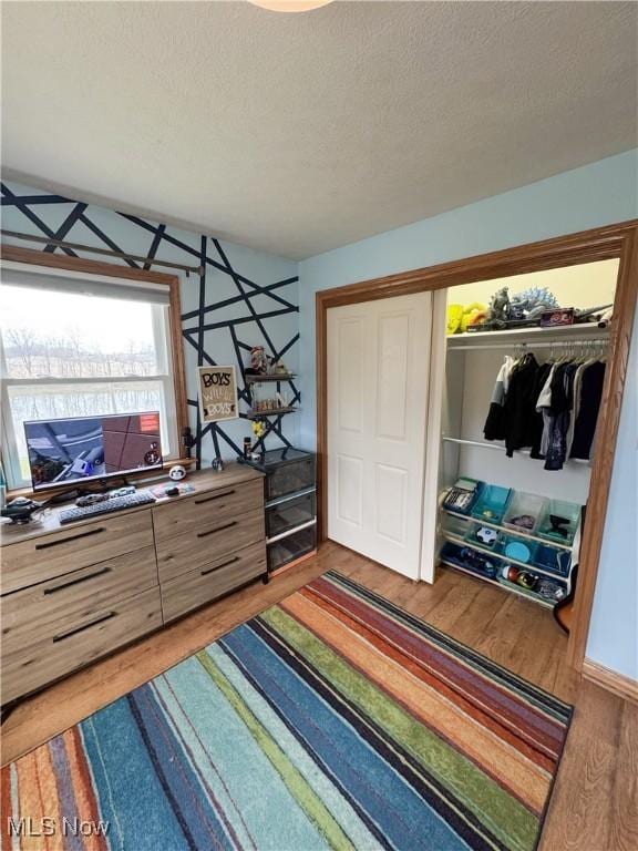bedroom featuring a closet, a textured ceiling, and wood finished floors