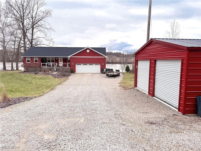 garage featuring a porch, gravel driveway, and a water view