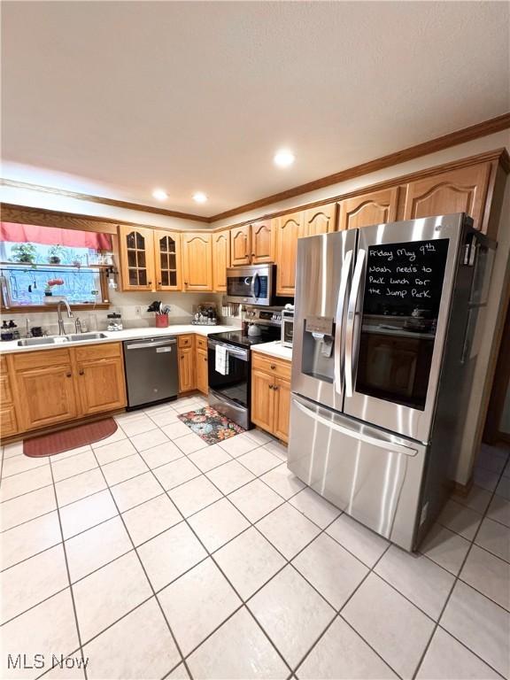 kitchen with light tile patterned floors, stainless steel appliances, light countertops, and a sink