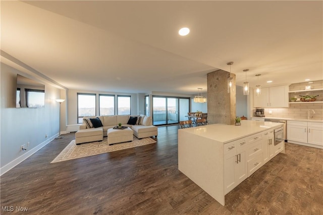 kitchen featuring dark wood-style floors, tasteful backsplash, white cabinetry, and a sink