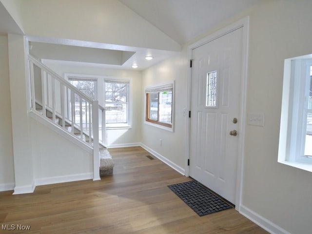 entryway featuring visible vents, baseboards, wood finished floors, stairs, and vaulted ceiling