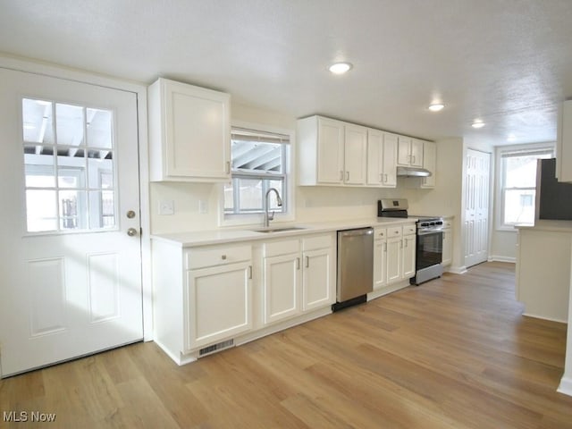 kitchen featuring under cabinet range hood, a sink, visible vents, appliances with stainless steel finishes, and light wood-type flooring