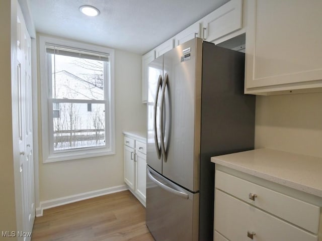 kitchen with light countertops, a wealth of natural light, freestanding refrigerator, and white cabinets