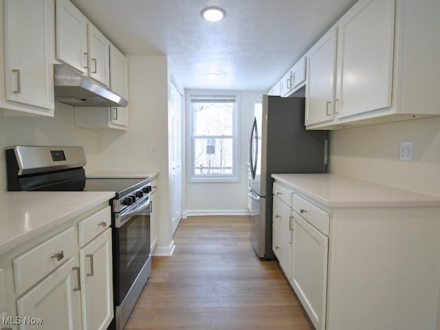 kitchen featuring light wood finished floors, appliances with stainless steel finishes, white cabinetry, and under cabinet range hood