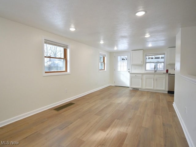 interior space featuring light wood finished floors, recessed lighting, visible vents, a textured ceiling, and baseboards