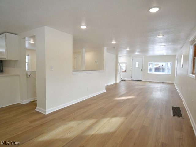 unfurnished living room with recessed lighting, light wood-type flooring, visible vents, and baseboards