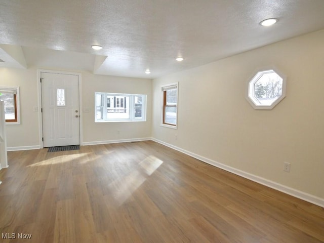 entryway with a healthy amount of sunlight, a textured ceiling, baseboards, and wood finished floors