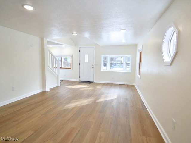 entrance foyer featuring plenty of natural light, stairs, baseboards, and wood finished floors