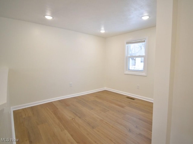 unfurnished room with recessed lighting, wood finished floors, visible vents, and baseboards