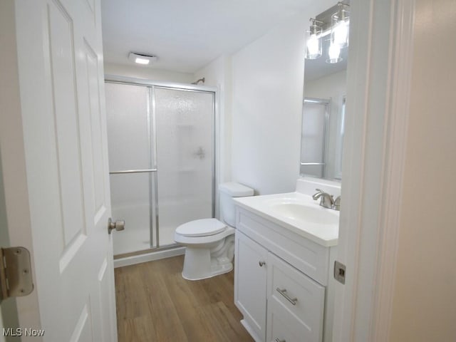 full bathroom featuring a stall shower, vanity, toilet, and wood finished floors