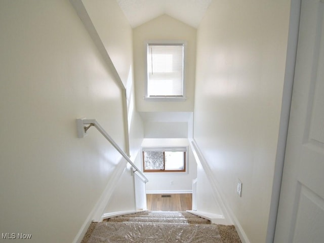 stairway with vaulted ceiling, wood finished floors, and baseboards