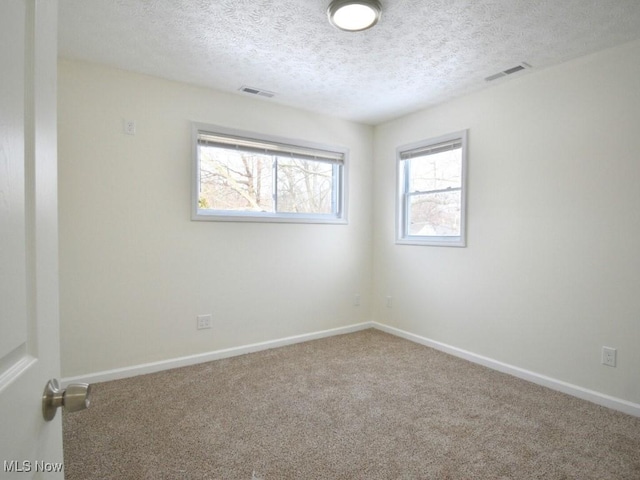 unfurnished room with carpet floors, visible vents, and baseboards