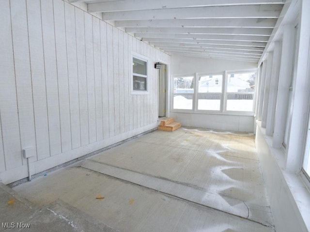 unfurnished sunroom featuring lofted ceiling with beams