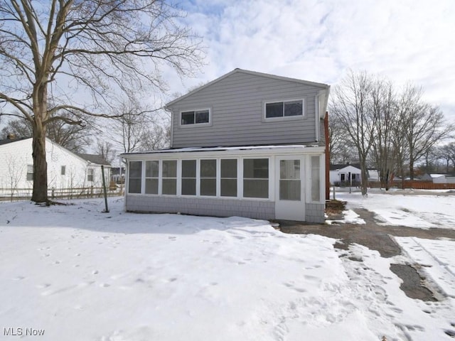 snow covered property featuring a sunroom