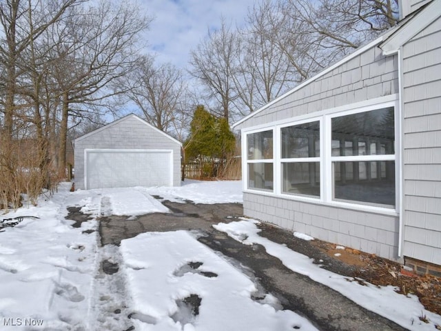 snowy yard featuring a garage and an outbuilding