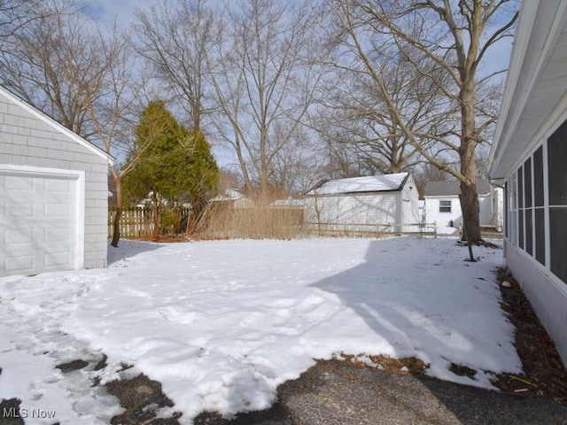 yard layered in snow with a sunroom, fence, and an outbuilding