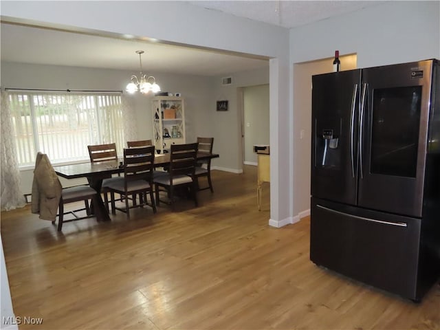 dining space featuring baseboards, light wood-style flooring, visible vents, and a notable chandelier