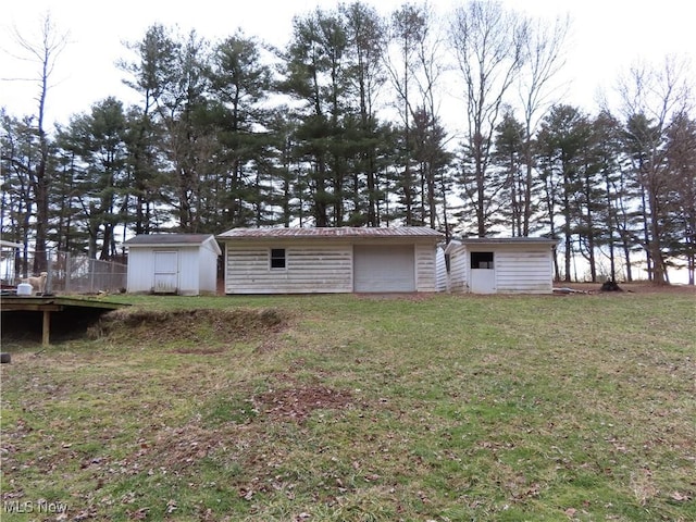 rear view of property with an outdoor structure, a storage unit, and a yard