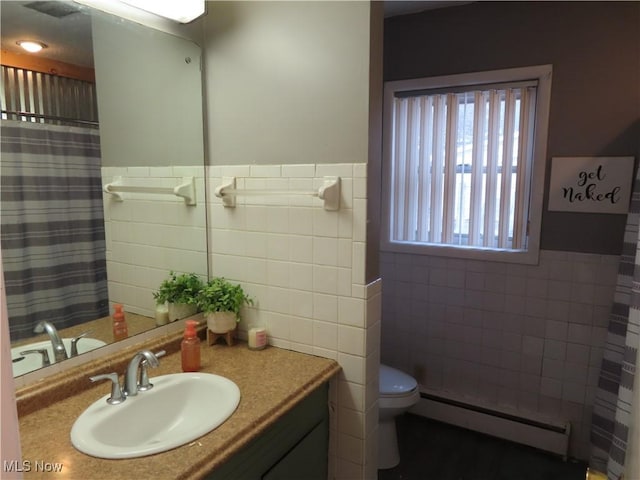 full bath with a baseboard heating unit, vanity, toilet, and tile walls