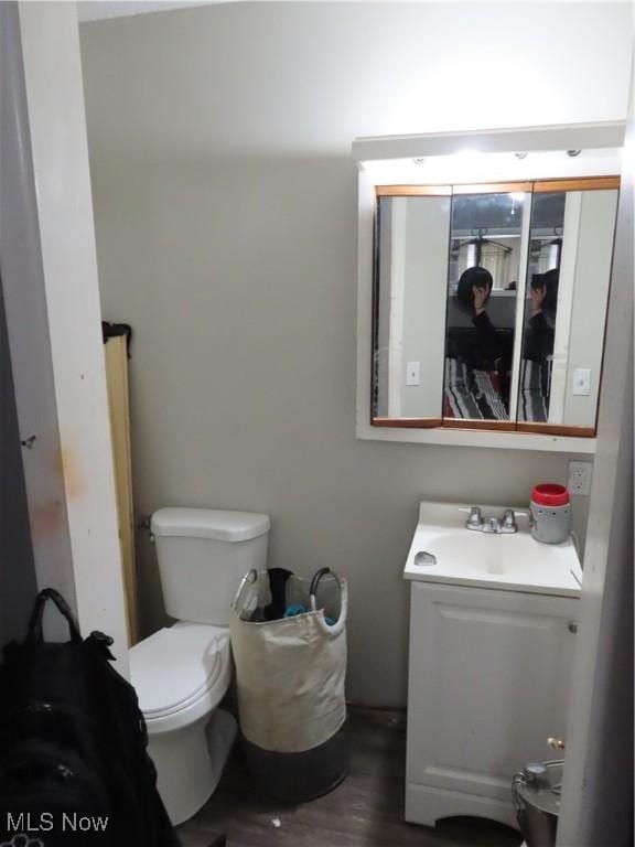 half bath featuring toilet, wood finished floors, and vanity