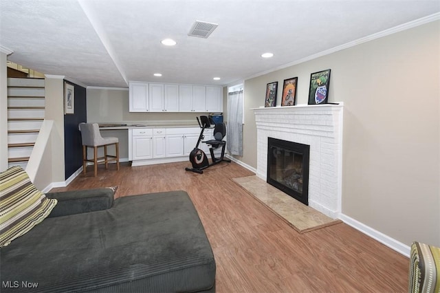 unfurnished living room featuring baseboards, crown molding, visible vents, and wood finished floors