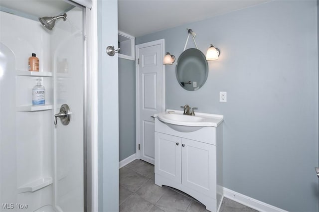 bathroom featuring a stall shower, vanity, and baseboards