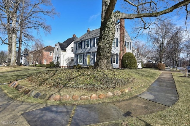 view of front of home featuring a chimney, a residential view, and a front yard