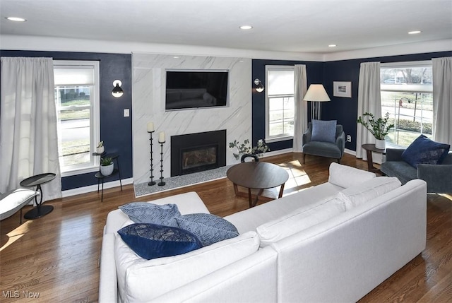 living room featuring a wealth of natural light, wood finished floors, and a premium fireplace