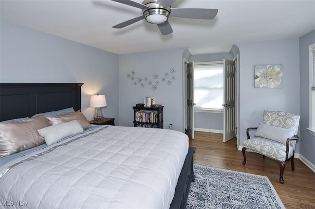 bedroom with a ceiling fan, baseboards, and wood finished floors