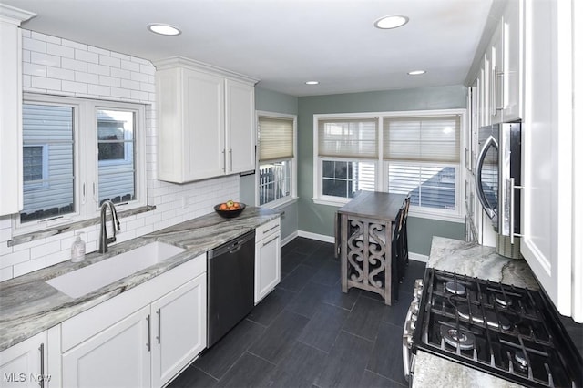 kitchen featuring a sink, white cabinetry, baseboards, dishwasher, and tasteful backsplash