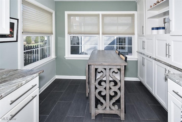 kitchen with open shelves, white cabinetry, and baseboards