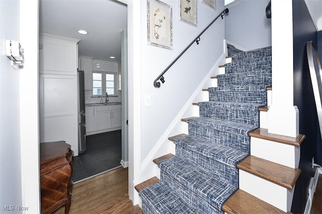 staircase with baseboards, wood finished floors, and recessed lighting