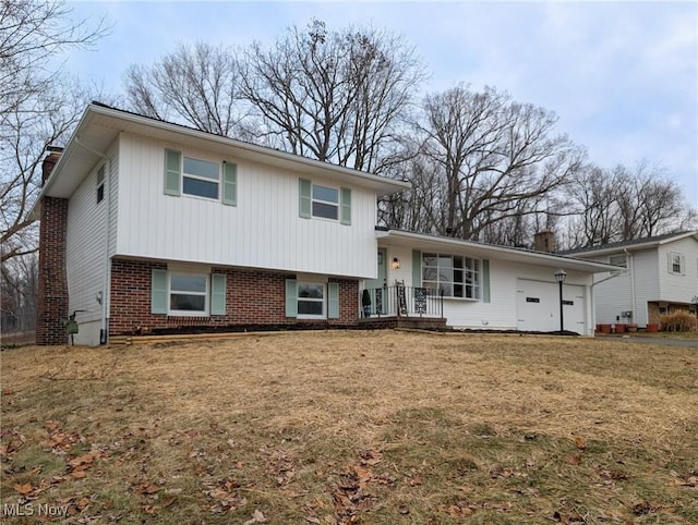 tri-level home with a front lawn, brick siding, a chimney, and an attached garage