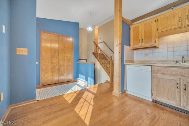 kitchen featuring dishwasher, backsplash, light countertops, light wood-style floors, and a sink