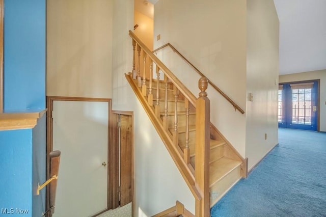 staircase with carpet floors and a towering ceiling