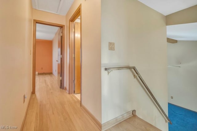 hallway with baseboards, light wood finished floors, and an upstairs landing