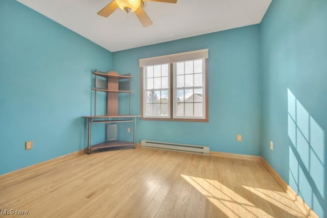 spare room with a ceiling fan, a baseboard radiator, baseboards, and wood finished floors