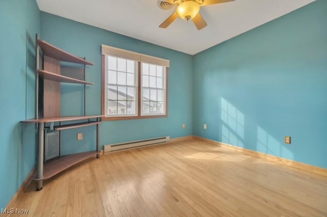 empty room with a ceiling fan, a baseboard radiator, baseboards, and wood finished floors