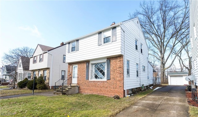 colonial home with an outbuilding, brick siding, a detached garage, and a front yard