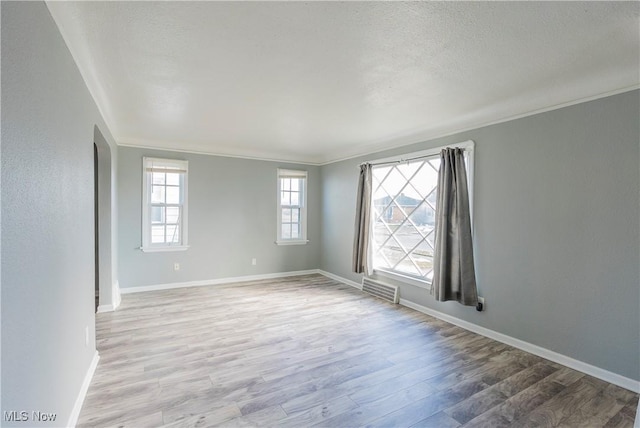 spare room with baseboards, visible vents, ornamental molding, wood finished floors, and a textured ceiling