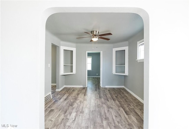 empty room featuring a healthy amount of sunlight, baseboards, and wood finished floors