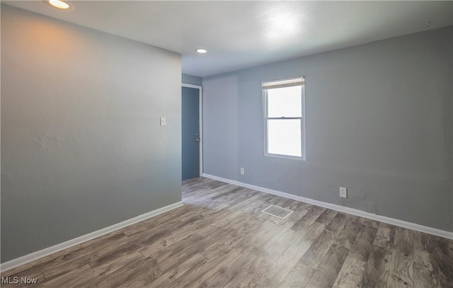 spare room featuring recessed lighting, wood finished floors, visible vents, and baseboards