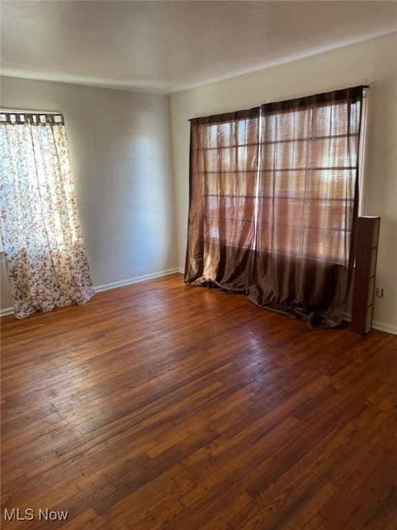 unfurnished room featuring hardwood / wood-style floors and baseboards