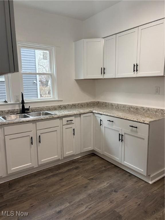 kitchen with dark wood-style floors, light countertops, white cabinetry, and a sink