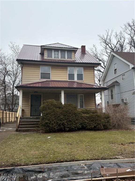 traditional style home with a porch, a front yard, metal roof, and a chimney