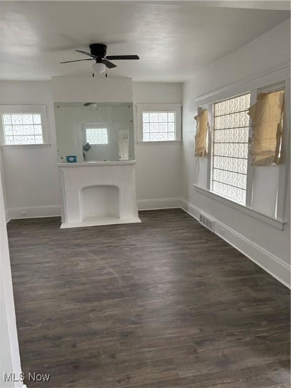 unfurnished living room featuring visible vents, dark wood-type flooring, a ceiling fan, and baseboards