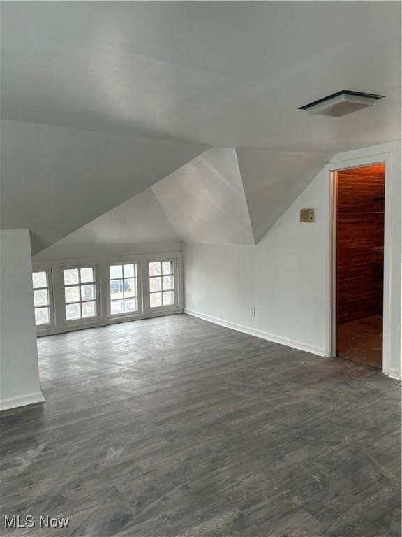 bonus room featuring baseboards, vaulted ceiling, and dark wood-style flooring