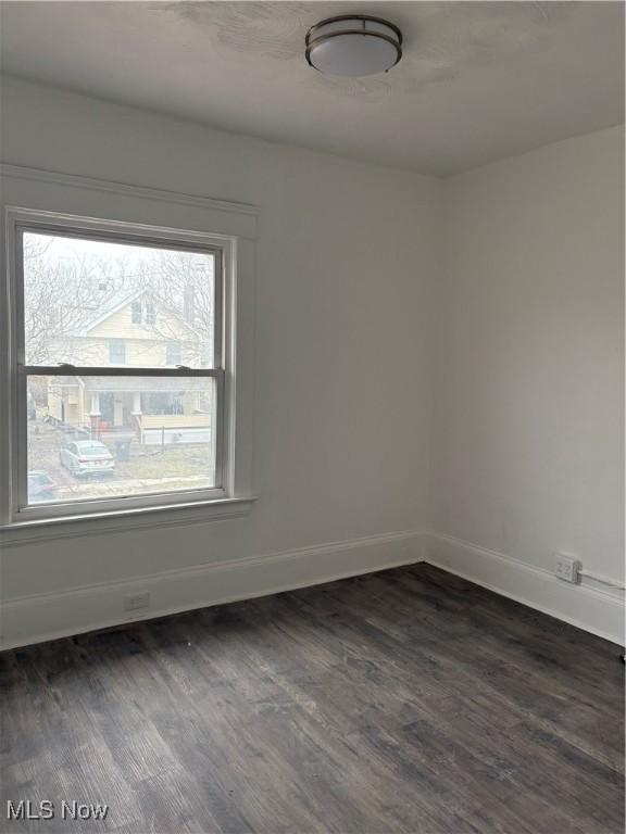 unfurnished room featuring dark wood-style flooring and baseboards